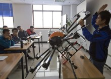In this Oct. 17, 2015 photo, an instructor explains the operation of a drone to students at a school run by TT Aviation Technology in Beijing. TT Aviation Technology Co. - and their instructors - are part of a cottage industry sprouting up in China, where drones are being deployed in rising numbers and touted as a game-changer in agriculture, logistics, film production and law enforcement. (AP Photo/Ng Han Guan)