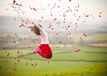 Girl jumping with rose petals in air